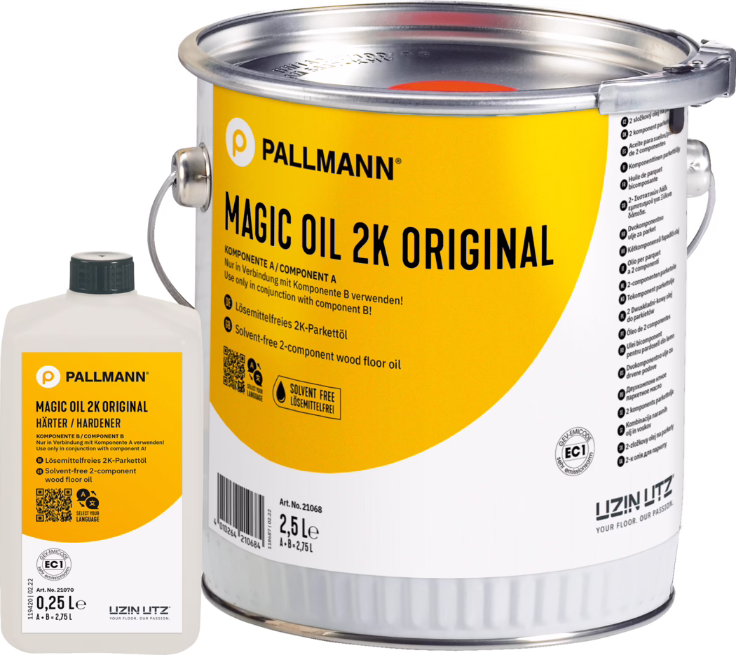 Plano detalle de una lata metálica con etiqueta amarilla PALLMANN Magic Oil 2K Original para suelos de madera (2,5 L) con una pequeña botella blanca de endurecedor (0,25 L) a su lado; la etiqueta muestra el logotipo de la marca, el nombre del producto, instrucciones de uso y un icono 'sin disolventes'; se ven el asa metálica y la tapa sellada; fotografía del producto sobre fondo blanco.